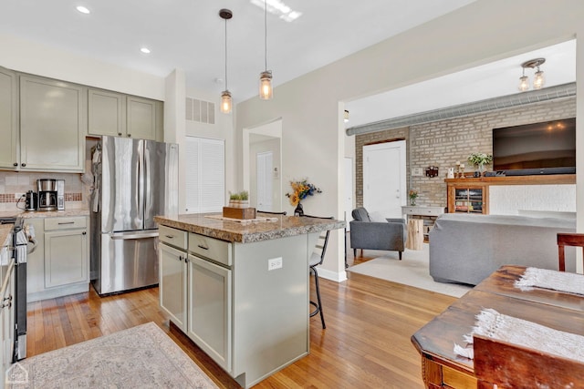 kitchen with a breakfast bar, pendant lighting, appliances with stainless steel finishes, open floor plan, and a kitchen island