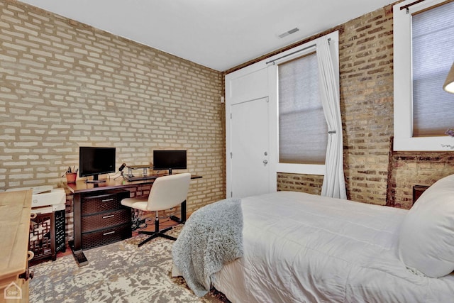 bedroom featuring brick wall and visible vents