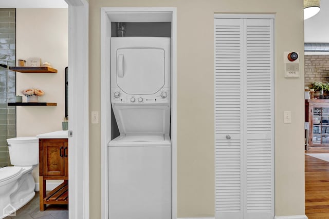 clothes washing area featuring laundry area, stacked washer and clothes dryer, and tile patterned floors