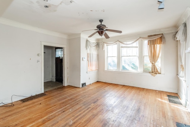 empty room featuring ornamental molding, light wood-type flooring, visible vents, and baseboards