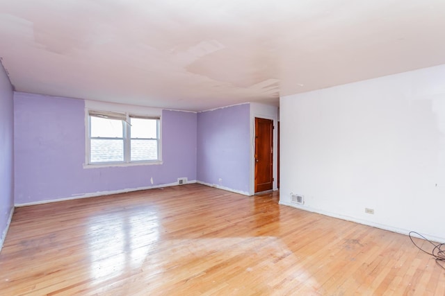 empty room featuring light wood-style flooring, visible vents, and baseboards