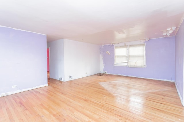 empty room featuring baseboards, visible vents, and light wood finished floors