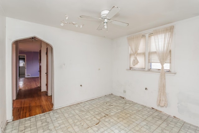 unfurnished room featuring a ceiling fan, arched walkways, visible vents, and light floors