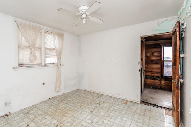 unfurnished room with a ceiling fan, log walls, and light floors