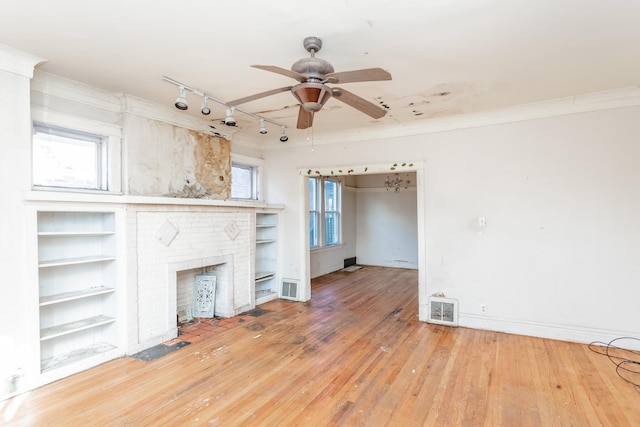 unfurnished living room featuring a brick fireplace, visible vents, plenty of natural light, and wood finished floors