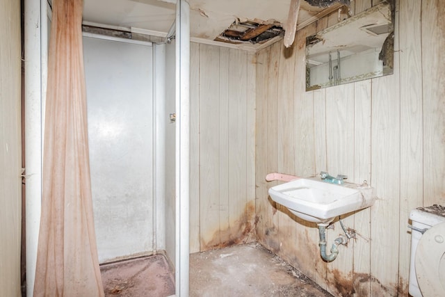 bathroom with a sink, washer / dryer, and wooden walls