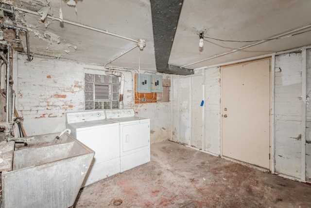 unfinished below grade area featuring electric panel, washer and clothes dryer, and a sink