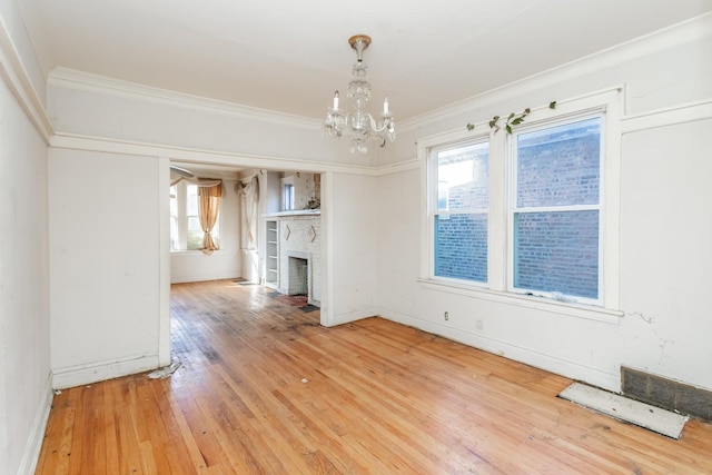 unfurnished living room featuring crown molding, a notable chandelier, a fireplace, and wood finished floors