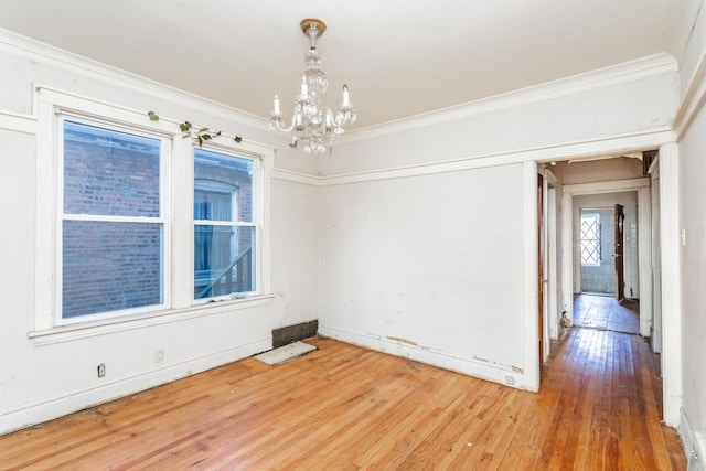 empty room featuring ornamental molding, a chandelier, and wood finished floors