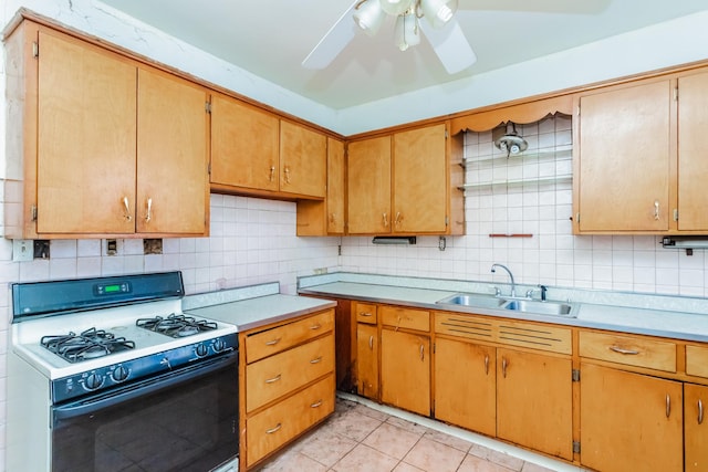 kitchen with a sink, light countertops, decorative backsplash, brown cabinets, and gas range gas stove