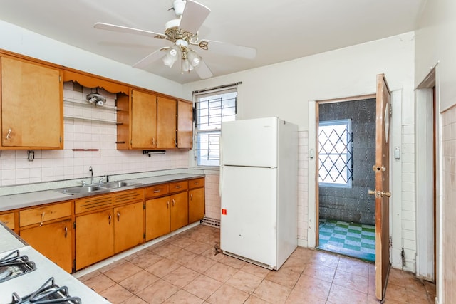 kitchen featuring open shelves, light countertops, brown cabinetry, freestanding refrigerator, and a sink