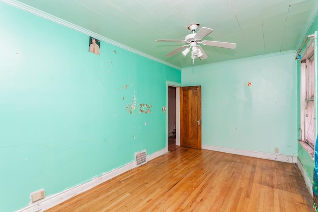 unfurnished room featuring light wood finished floors, baseboards, visible vents, ceiling fan, and crown molding