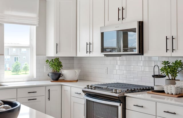 kitchen featuring white cabinets, stainless steel appliances, and backsplash