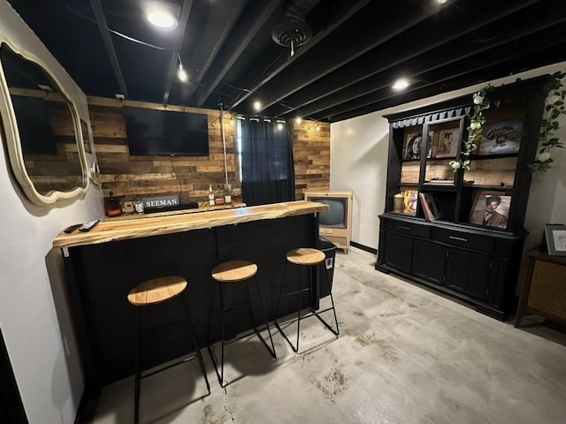 bar featuring a dry bar, wood walls, and concrete flooring