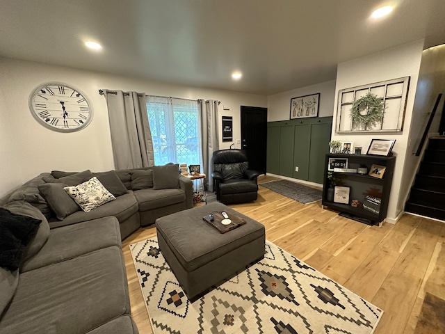 living room featuring light wood-style flooring, recessed lighting, and stairway