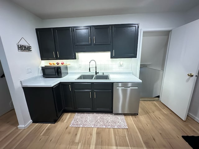 kitchen with dark cabinets, a sink, light countertops, dishwasher, and light wood finished floors