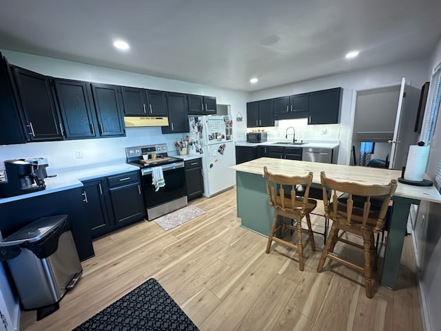 kitchen featuring light wood-style flooring, appliances with stainless steel finishes, dark cabinets, light countertops, and under cabinet range hood