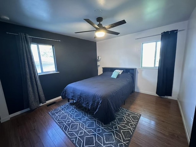 bedroom featuring dark wood-style floors, multiple windows, baseboards, and a ceiling fan