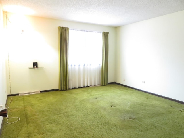 empty room featuring a textured ceiling, carpet, visible vents, and baseboards