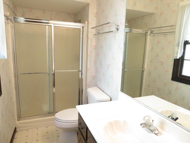 full bathroom featuring wallpapered walls, toilet, a stall shower, vanity, and tile patterned floors