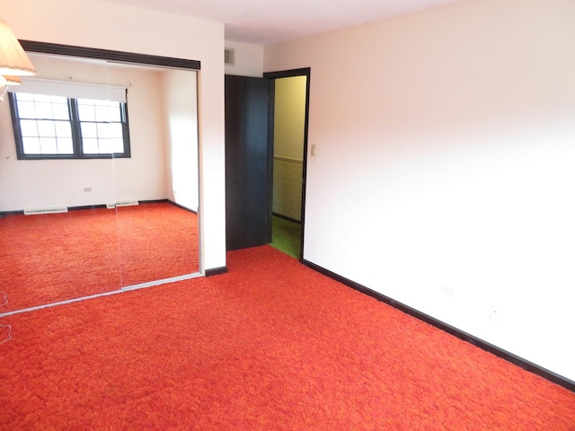 carpeted spare room featuring visible vents and baseboards