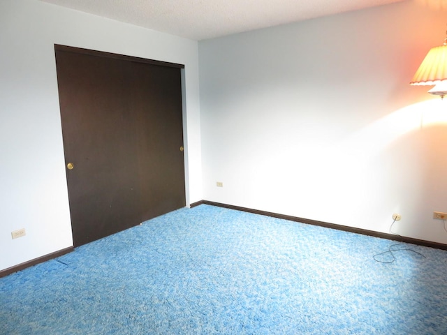 unfurnished bedroom featuring carpet, baseboards, and a closet