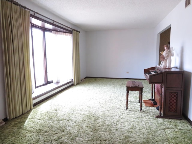 spare room with a textured ceiling, a baseboard radiator, visible vents, baseboards, and carpet