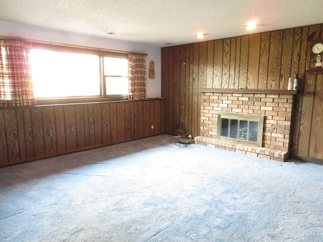 unfurnished living room with carpet, a fireplace, wooden walls, and a textured ceiling