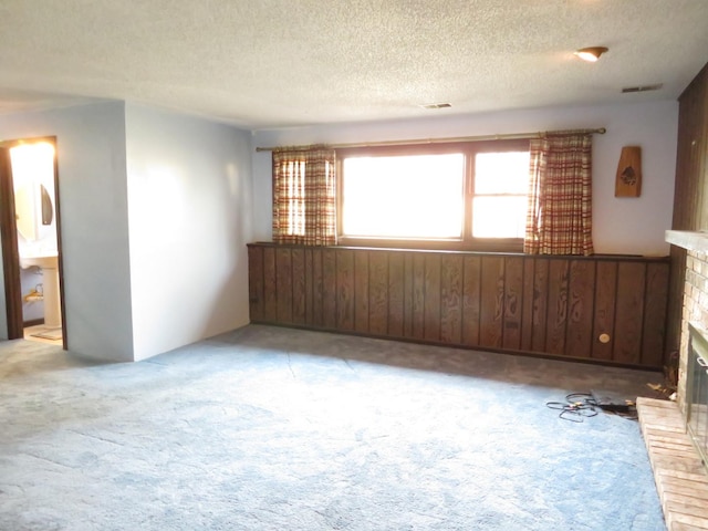 empty room with light colored carpet, a brick fireplace, and visible vents