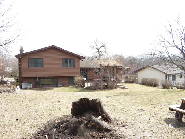 rear view of house with a yard, a chimney, and a wooden deck