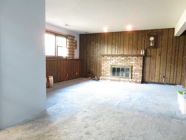 unfurnished living room featuring carpet floors, a brick fireplace, wooden walls, and a textured ceiling