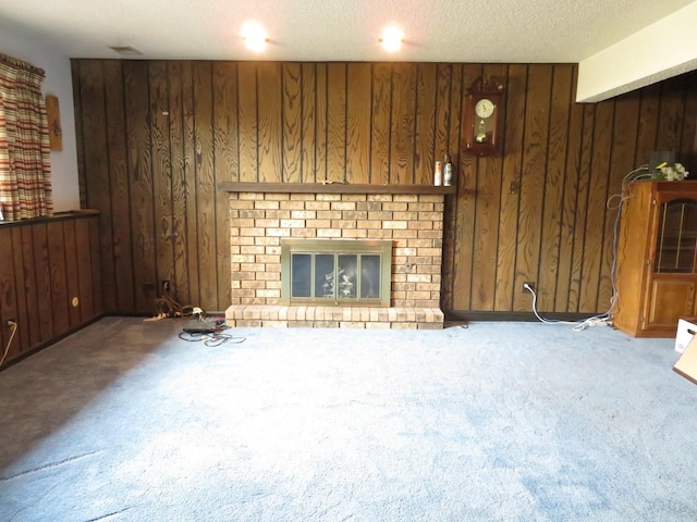 unfurnished living room featuring a textured ceiling, carpet floors, a fireplace, and wooden walls