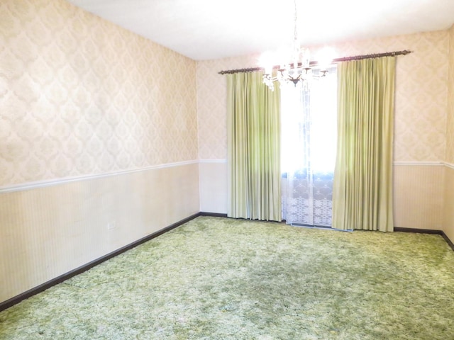 carpeted spare room featuring a chandelier, wainscoting, and wallpapered walls