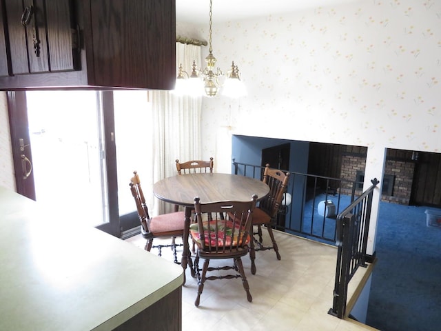 dining space with wallpapered walls, a brick fireplace, light floors, and an inviting chandelier