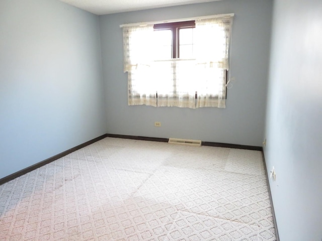 spare room with carpet floors, visible vents, and baseboards