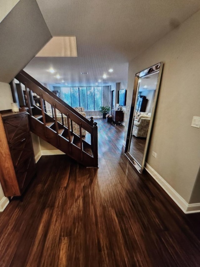 hallway with dark wood-type flooring and baseboards