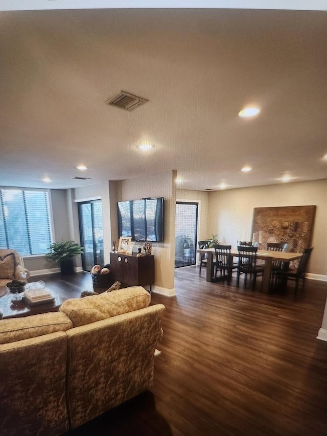 living area with baseboards, dark wood-type flooring, visible vents, and recessed lighting