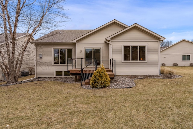 back of house with a deck, a shingled roof, and a lawn