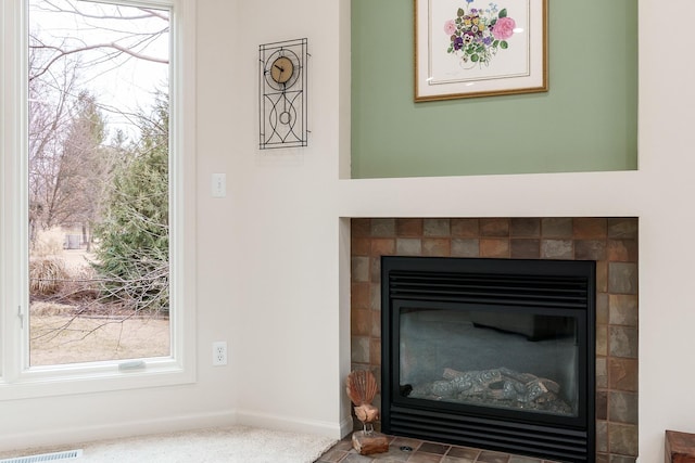 details featuring a tile fireplace, visible vents, and baseboards