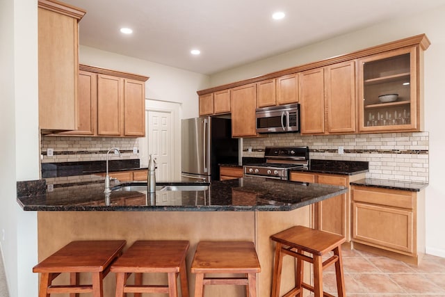 kitchen with stainless steel appliances, backsplash, a sink, a peninsula, and a kitchen breakfast bar