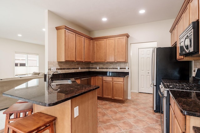 kitchen featuring stainless steel appliances, a peninsula, a sink, a kitchen breakfast bar, and open floor plan