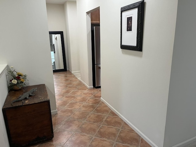 hall featuring light tile patterned flooring and baseboards