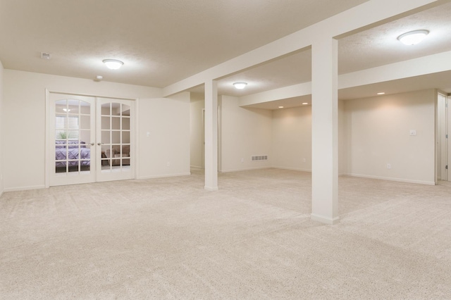 basement with french doors, visible vents, light carpet, a textured ceiling, and baseboards