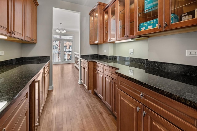 kitchen featuring glass insert cabinets, brown cabinetry, and dark stone countertops