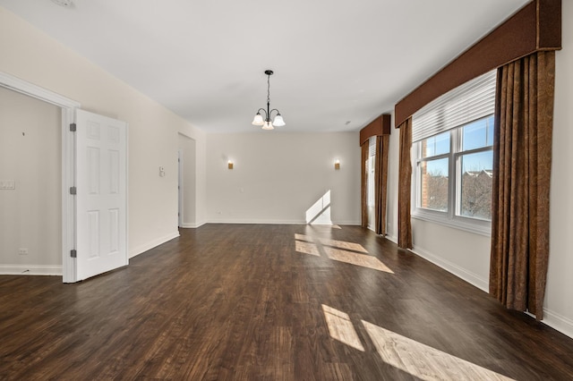 unfurnished dining area featuring dark wood-style floors, a chandelier, and baseboards