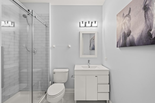 bathroom featuring toilet, a shower stall, vanity, and baseboards