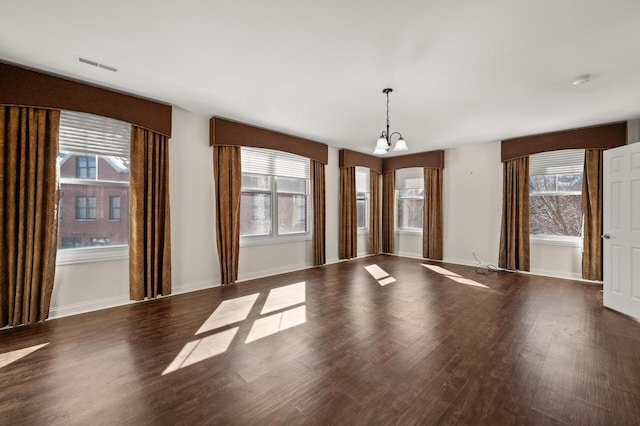 interior space with visible vents, dark wood finished floors, baseboards, and an inviting chandelier