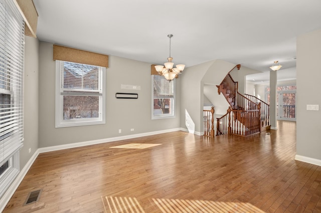 interior space featuring baseboards, stairway, a chandelier, and wood finished floors