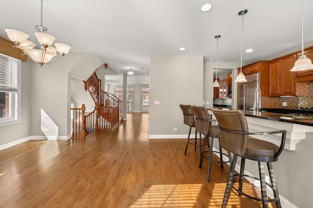 kitchen with dark countertops, decorative light fixtures, stainless steel built in fridge, and a breakfast bar area