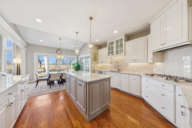 kitchen with a sink, a center island, white cabinets, light wood finished floors, and white gas cooktop